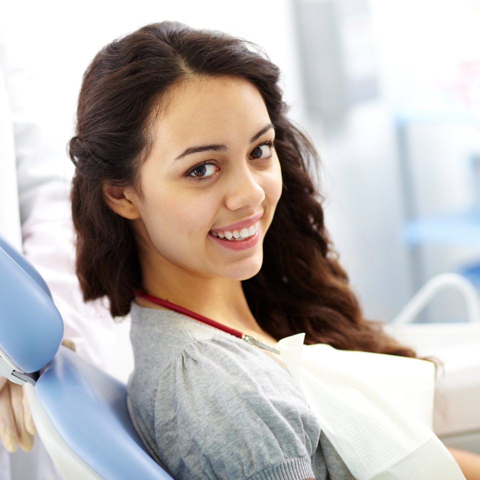 young woman smiling warmly in the dental chair