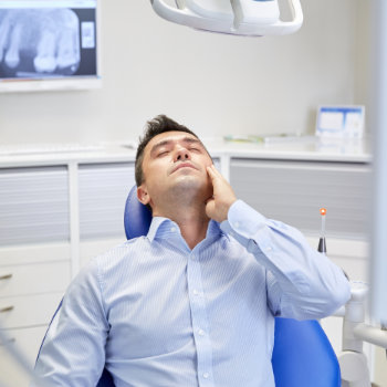 a man is sitting with a toothache in a dental office