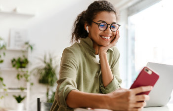 smiling girl with glasses looks at a smartphone