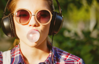 girl listening to music on headphones and chewing bubble gum