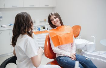A dentist explaining the dental procedure to the woman sitting in a dental chair