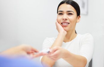 A woman with severe toothache at a front desk of an emergency dentist's office