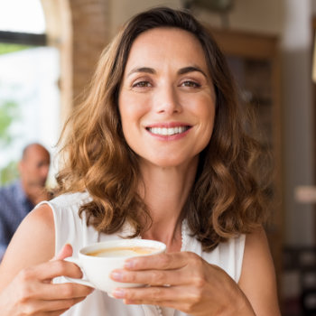 Mature woman smiling holding cup Roswell Complete Dentistry care