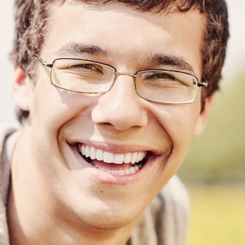 Young man with glasses smiling Roswell Complete Dentistry patient